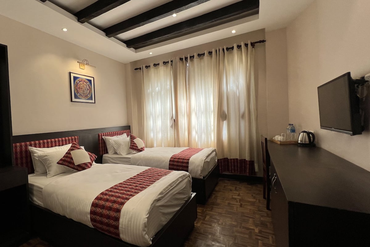 A hotel room with two beds, a large mirror, a flat-screen TV, and a window with curtains.