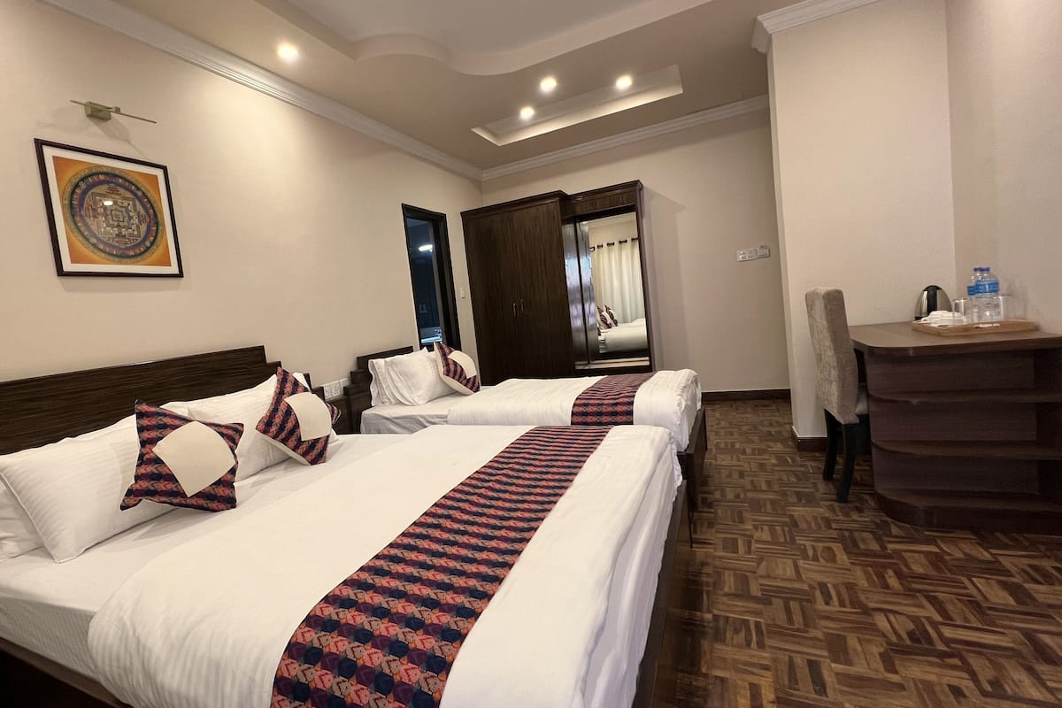 A hotel room with two beds, a desk, and a mirror.