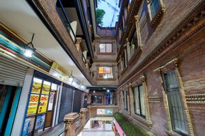 Une cour intérieure aux murs de briques, dotée d’un espace central ouvert et offrant une vue sur le ciel grâce à une verrière.