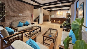 Eine geräumige Lobby mit Backsteinwand, Holzmöbeln, einer Rezeption und einer Buddha-Statue.