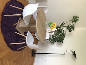 Cozy dining area with a wooden table and four chairs, complemented by a potted plant and floor lamp.