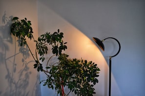 A cozy corner with a floor lamp and a potted plant.