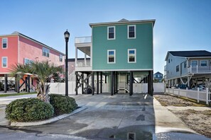 Une rangée de maisons colorées, avec un bâtiment central vert, une allée couverte et un ciel dégagé.