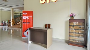 A hotel reception area with a reception desk, a staircase, and a large OYO sign on the wall. - OYO 838 Sanjaya Homestay Syariah (Bukittinggi)