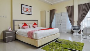 A neatly arranged bedroom with a bed, bedside table, wardrobe, and a chair. - OYO 838 Sanjaya Homestay Syariah (Bukittinggi)