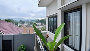 A balcony with a view of a cityscape, including buildings and mountains in the distance. - OYO 838 Sanjaya Homestay Syariah (Bukittinggi)