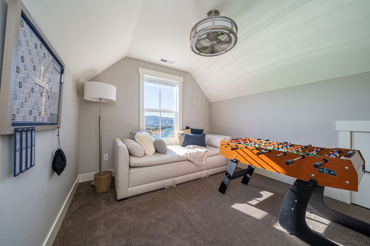 Ett mysigt rum med ett fotbollsspel, en soffa, en lampa och ett fönster med utsikt.