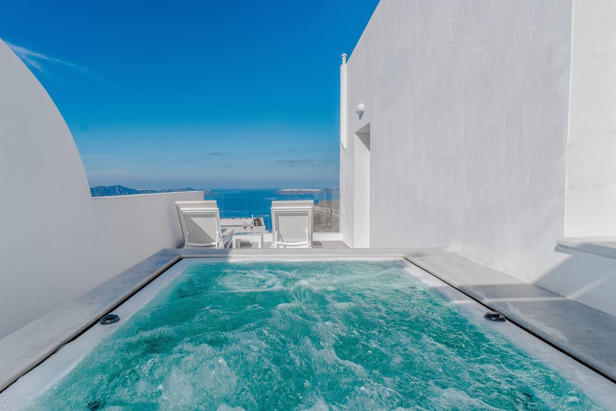 A rooftop infinity pool with a clear view of the sea and distant mountains.