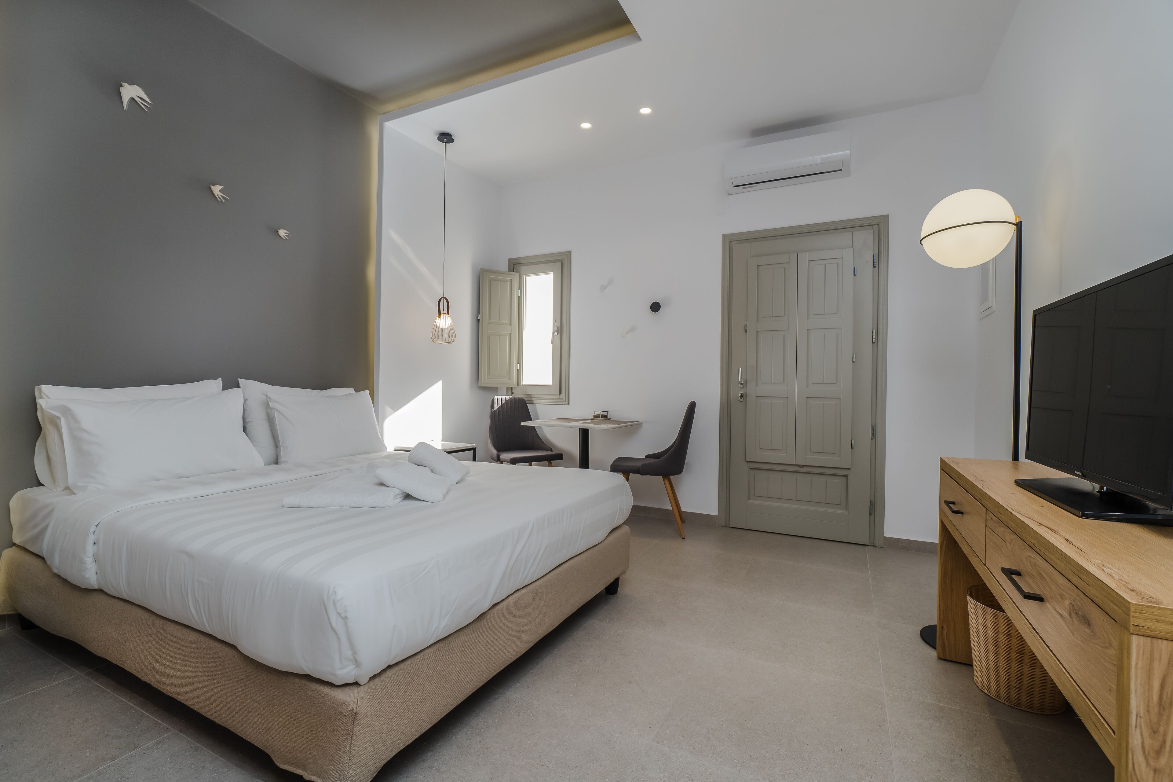 A modern bedroom with a bed, desk, chair, and TV.