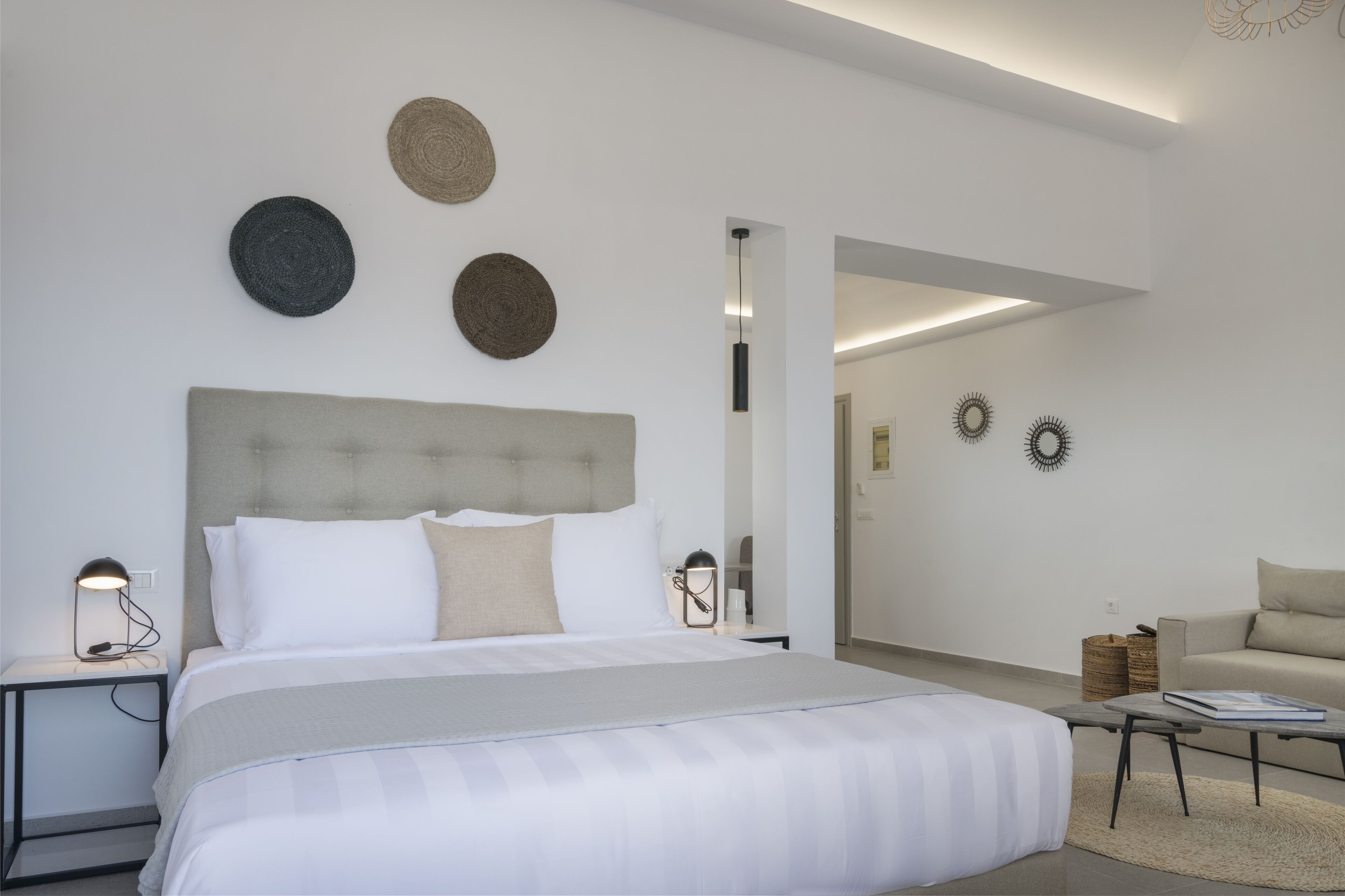 Une chambre d’hôtel moderne avec un grand lit, des tables de chevet, une lampe de lecture et une petite table sur laquelle est posé un livre.