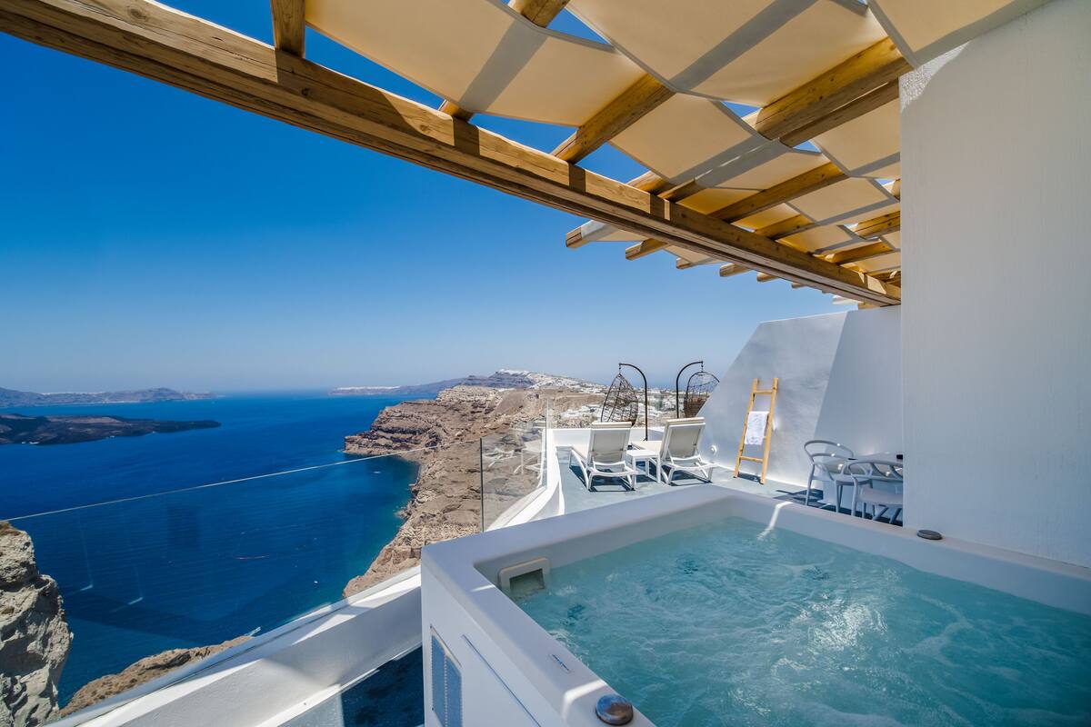A luxurious outdoor hot tub with a clear view of the sea and rocky coastline.