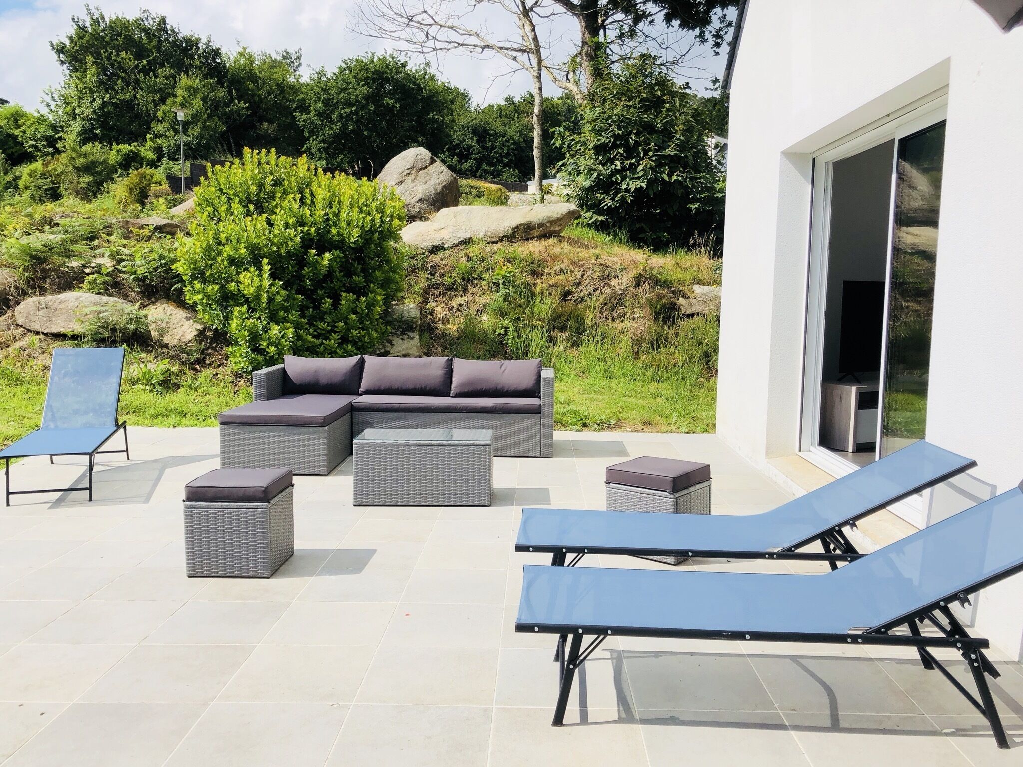 A patio with a sectional sofa, two lounge chairs, and a small table.