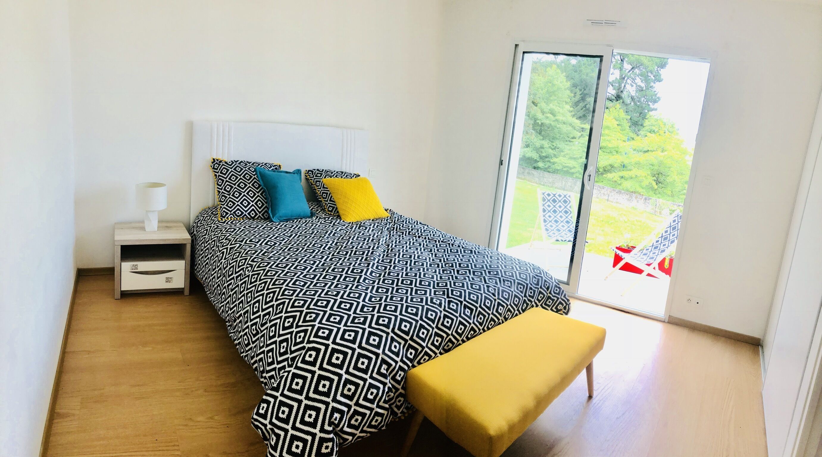 Una camera da letto con un letto, un comodino e una panca.