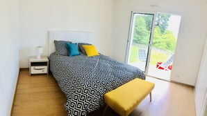 A bedroom with a bed, bedside table, and a bench. - House 8 persons Tréboul (Douarnenez)