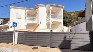 A multi-story residential building with balconies, a pedestrian crossing sign, and a gated entrance. - Villa Chiara (Crikvenica)