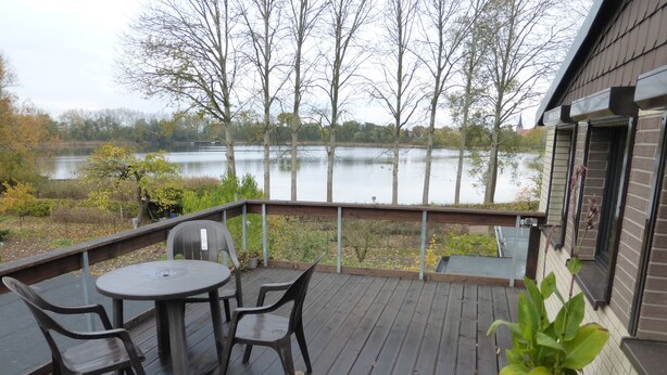 A wooden deck with a table and chairs, overlooking a lake. - Your apartment directly on the Gantikow lake (Gantikow)