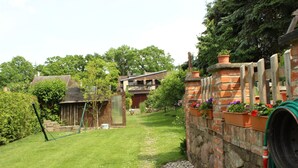 A garden with a brick wall, a swing set, and a hose coiled on the wall. - Your apartment directly on the Gantikow lake (Gantikow)