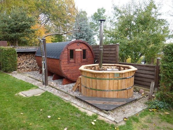 Une cabane en bois rustique, dotée d’un sauna et d’une grande cuve.