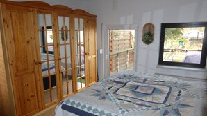 A bedroom with a wooden wardrobe, a bed with a quilt, a window with a view of the outdoors, and a door leading outside. - Your apartment directly on the Gantikow lake (Gantikow)