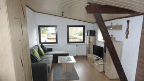 A modern living room with a sofa, coffee table, TV, and wooden cabinets. - Your apartment directly on the Gantikow lake (Gantikow)