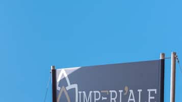 A banner with the text "IMPERIALE" and a logo, mounted on a metal frame against a clear blue sky.