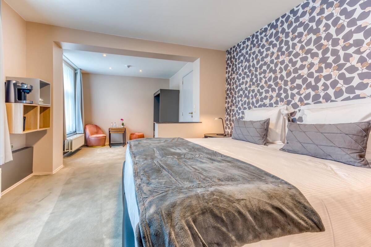 Une chambre moderne avec un grand lit, une armoire, une chaise et une petite table.