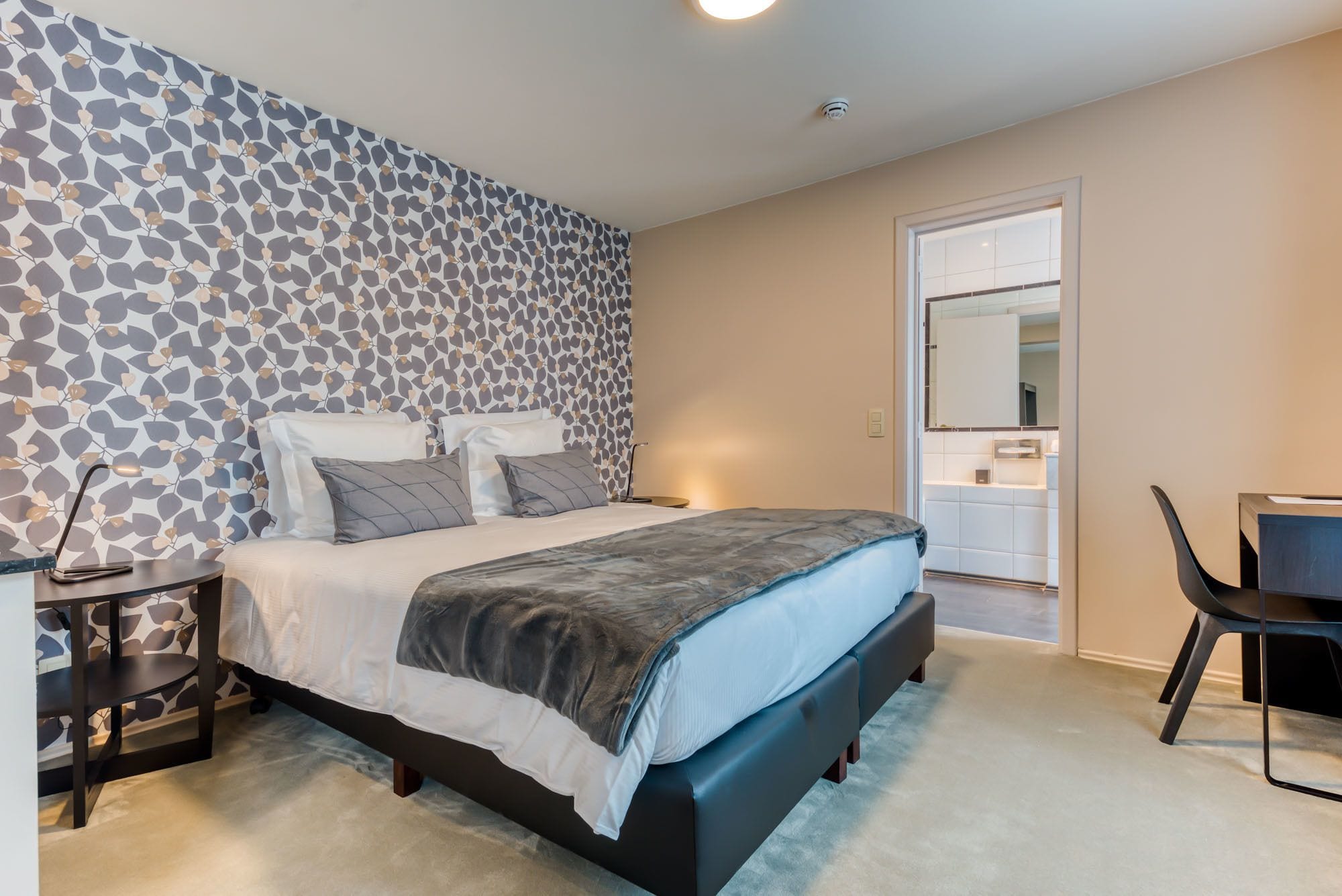 A modern bedroom with a bed, bedside table, and a chair.