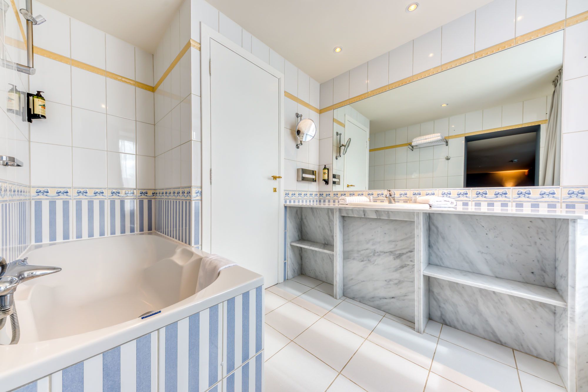 A modern bathroom with a freestanding bathtub, a large mirror, and a marble vanity.
