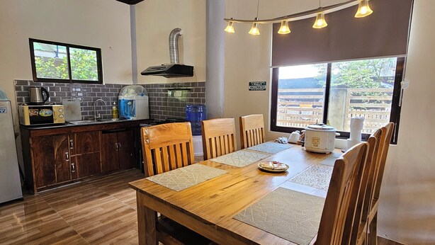 Une cuisine moderne avec un coin repas, comprenant une table en bois, des chaises et une vue dégagée sur l’extérieur grâce à une grande fenêtre.