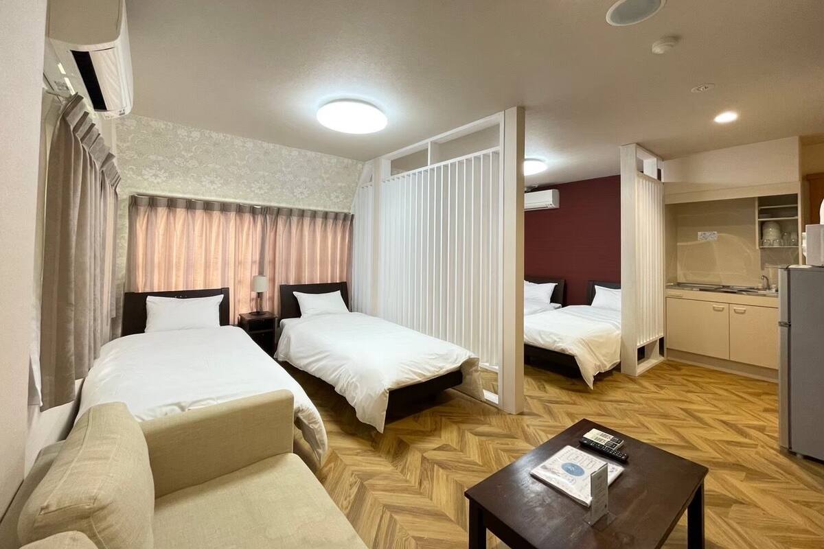 Une chambre d’hôtel avec deux lits, un canapé, une petite table et une kitchenette.