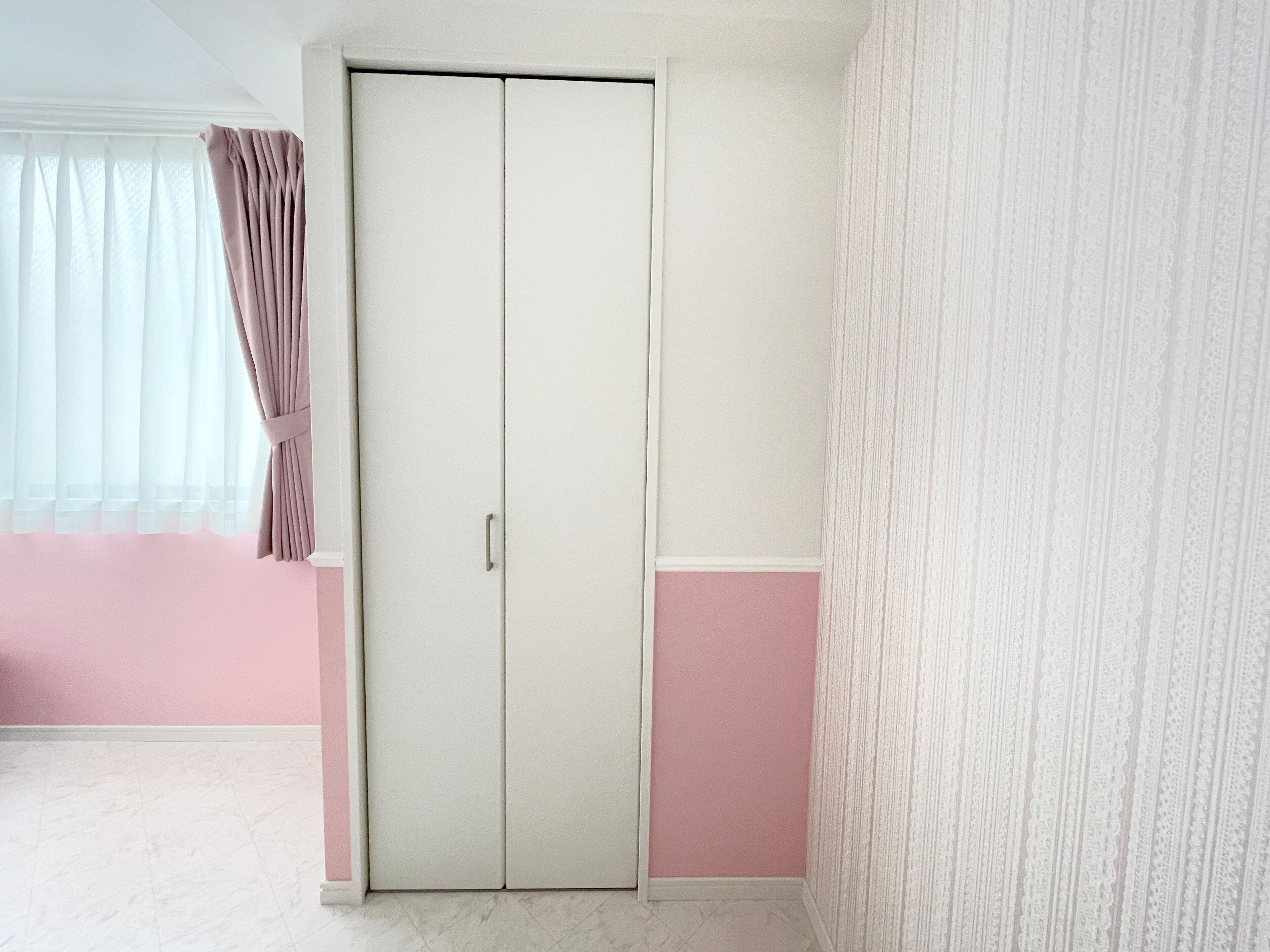 Una habitación con puerta doble, paredes rosas y papel tapiz estampado.