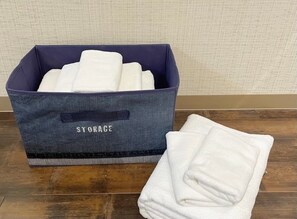Une boîte de rangement étiquetée « RANGEMENT » contenant des serviettes blanches à l’intérieur et une serviette à l’extérieur.