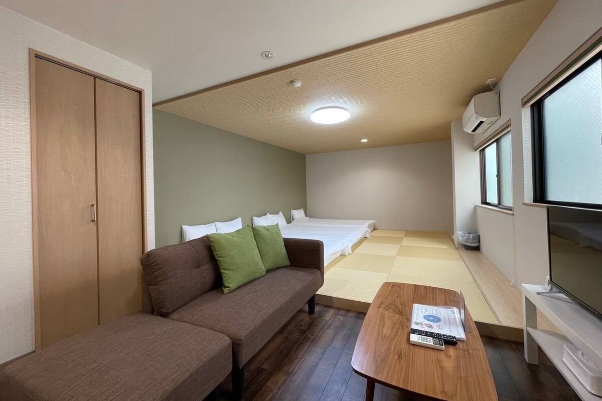 Une pièce de taille modeste comprenant un canapé, une petite table, un lit et un téléviseur.