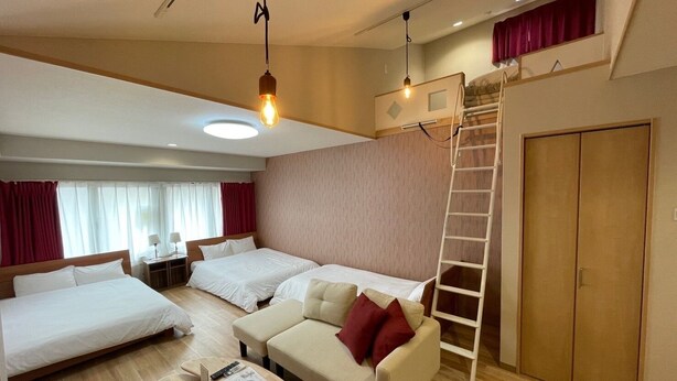Een hotelkamer met twee bedden, een bank, een ladder en een kledingkast.