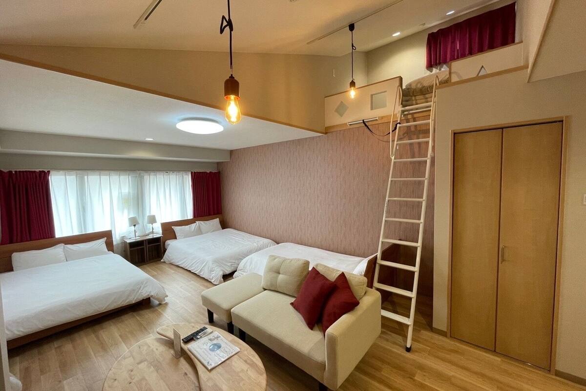 Une chambre d’hôtel avec deux lits, un canapé, une échelle et une armoire.