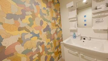 A bathroom with a colorful animal-themed wall, a white sink, and a mirror above it.