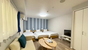 Een hotelkamer met twee enkele bedden, een bank, een klein tafeltje, een televisie en een kledingkast.