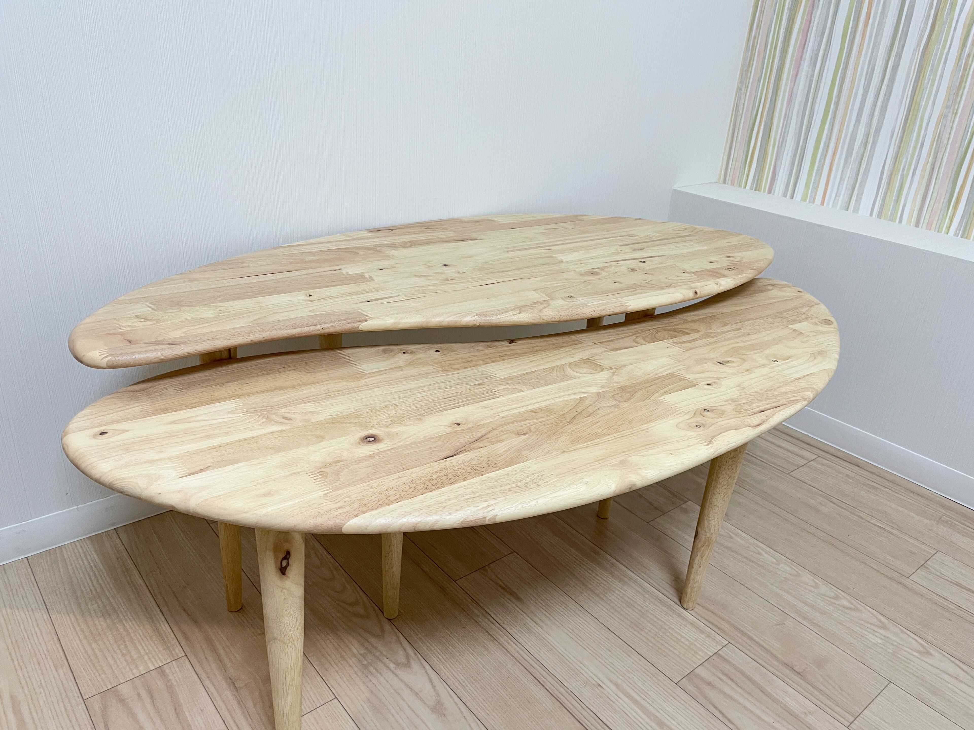 A wooden bench with a curved design, positioned against a wall with a striped pattern.