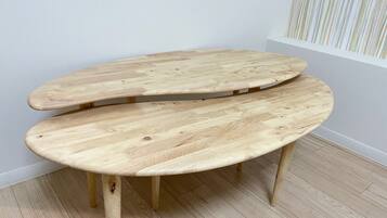 A wooden bench with a curved design, positioned against a wall with a striped pattern.
