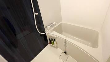A bathroom with a bathtub, a shower, and a toilet. There are toiletries on the wall.