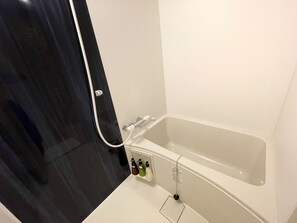 Une salle de bain avec une baignoire, une douche et des toilettes. Des articles de toilette sont accrochés au mur.