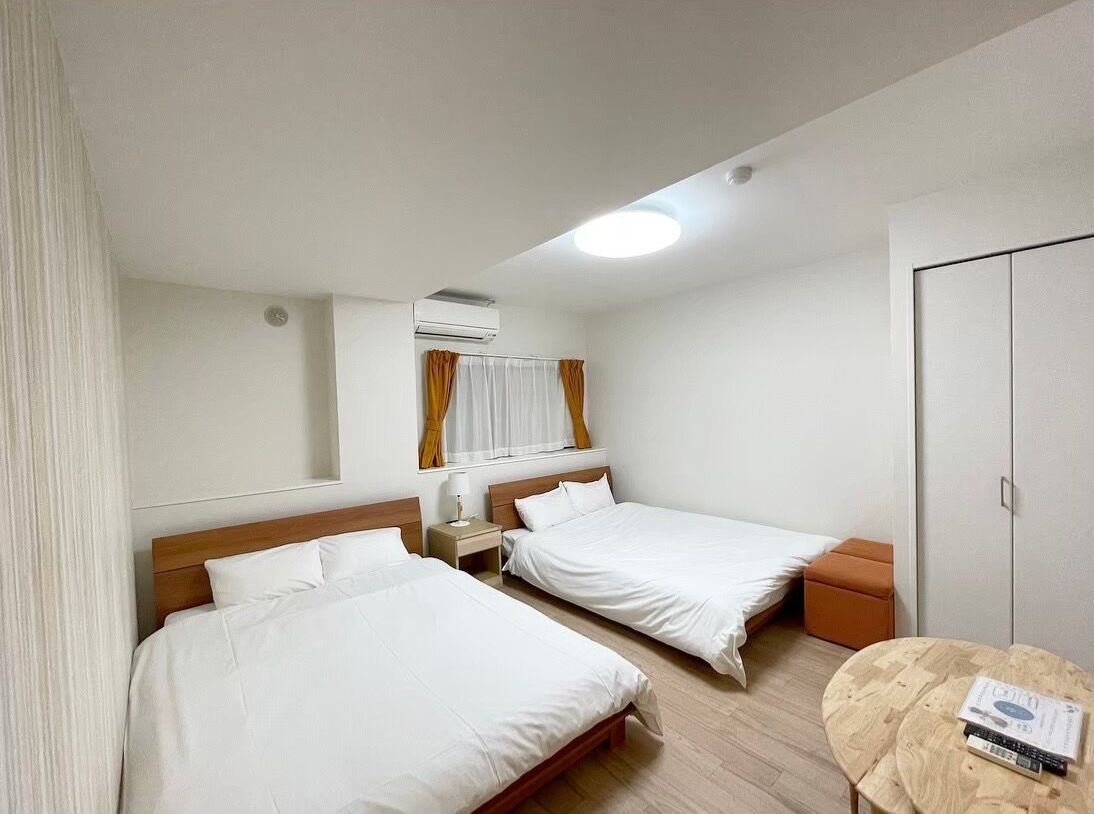 Een hotelkamer met twee enkele bedden, een houten vloer, een ronde tafel en een kledingkast.