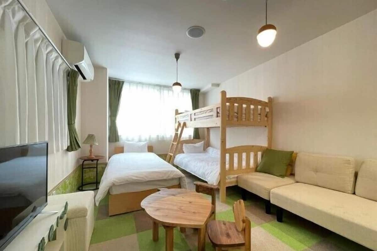 Une chambre d’hôtel avec des lits superposés, un canapé, une télévision et une petite table.