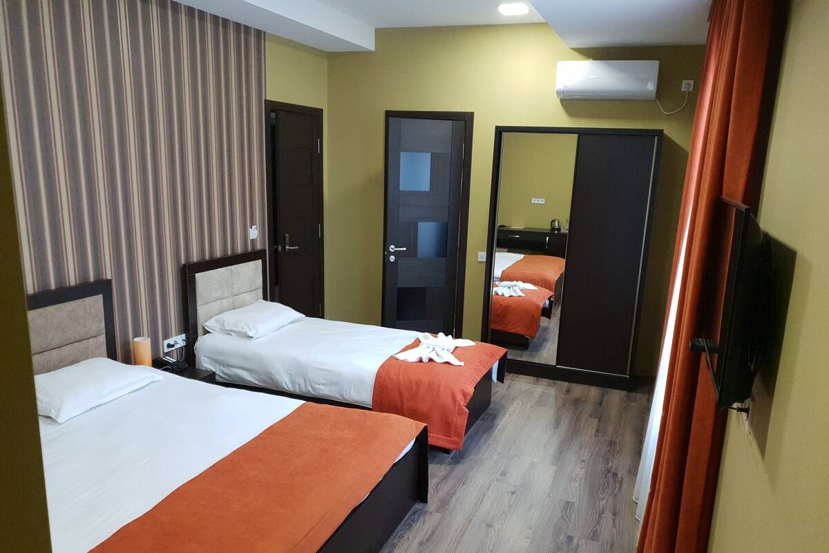 A hotel room with two beds, a mirror, and a TV.