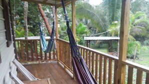 A wooden deck with a hammock and a bench.
