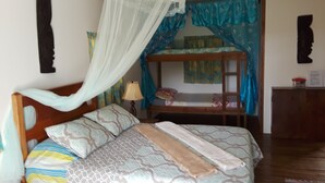 A bedroom with a bed, a nightstand, a lamp, a bunk bed, and a wardrobe.