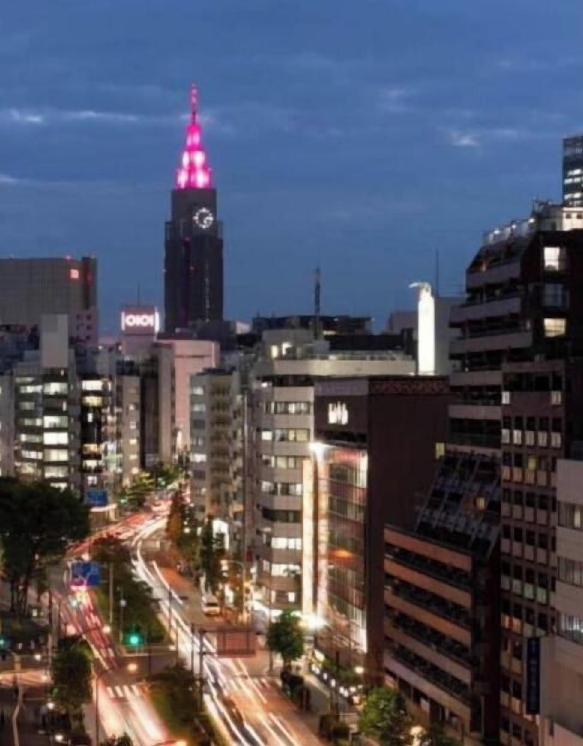 A cityscape with a prominent building featuring a spire with lights, surrounded by other high-rise buildings.