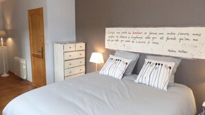 A bedroom with a bed, a dresser, a lamp, and a wall with a quote. - Chambres d'hôtes La Vergne (Saint-Martin-des-Combes)