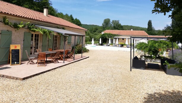 A rustic outdoor seating area with tables and chairs, a gravel path, and a building with a tiled roof. - Chambres d'hôtes La Vergne (Saint-Martin-des-Combes)
