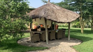 A thatched-roof outdoor dining area with wicker furniture and a stone pathway.